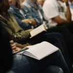 People sitting in chairs with bibles in their laps.